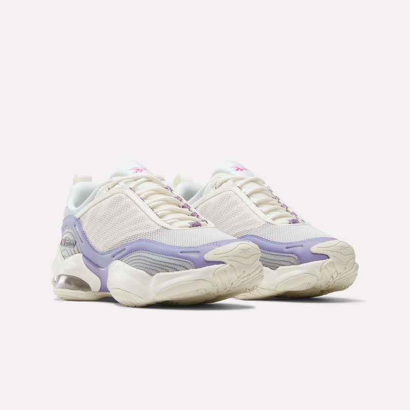 The Reebok Women’s DMX Series 3000 Shoes feature white and light purple mesh uppers, chunky soles, and lavender accents, delivering lightweight support and an ultra-cushioned feel—all showcased on a plain white background.