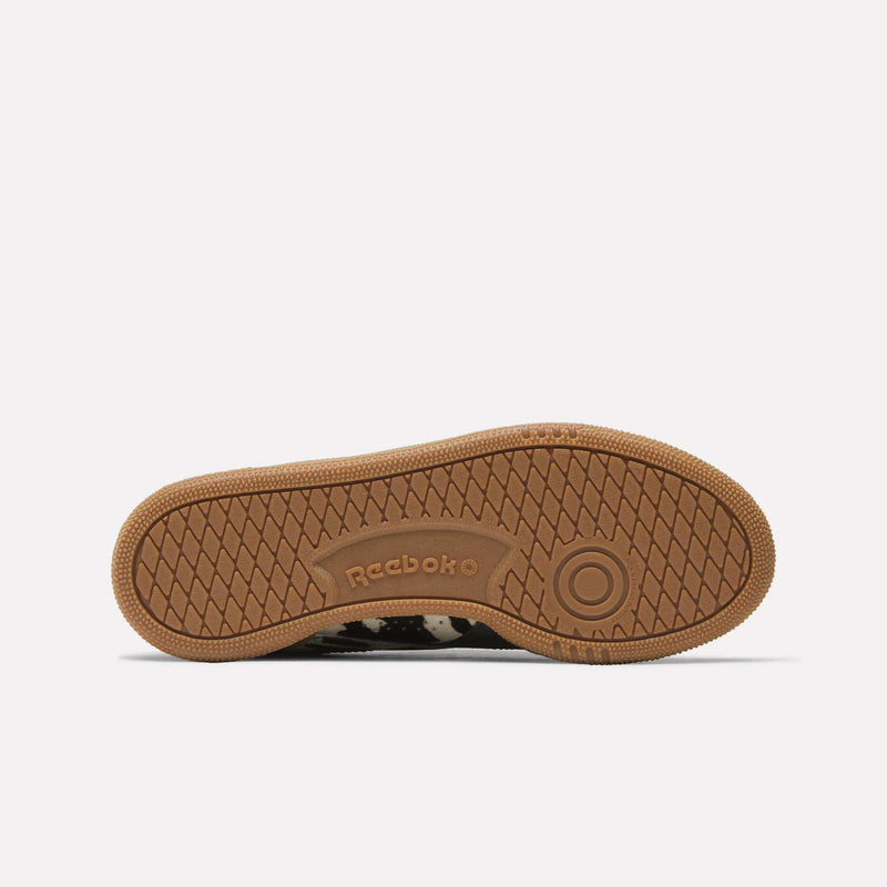 The image shows the sole of the Reebok Women's Club C Grounds UK Shoes, viewed from below. The brown outsole displays a textured herringbone pattern with circular details and an embossed Reebok logo in the center.