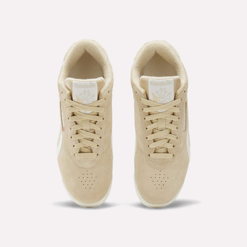 Top view of a pair of Women's Freestyle Lo Shoes by Reebok in beige with white soles and beige laces, featuring the Reebok logo on the tongue and side. The sneakers are placed side by side on a plain white background.
