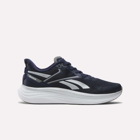 The Reebok Men's Viva Speed Shoes in navy blue feature white and silver accents, a thick cushioned white sole for comfort, and a low-cut design. Shown in side profile against a plain background.