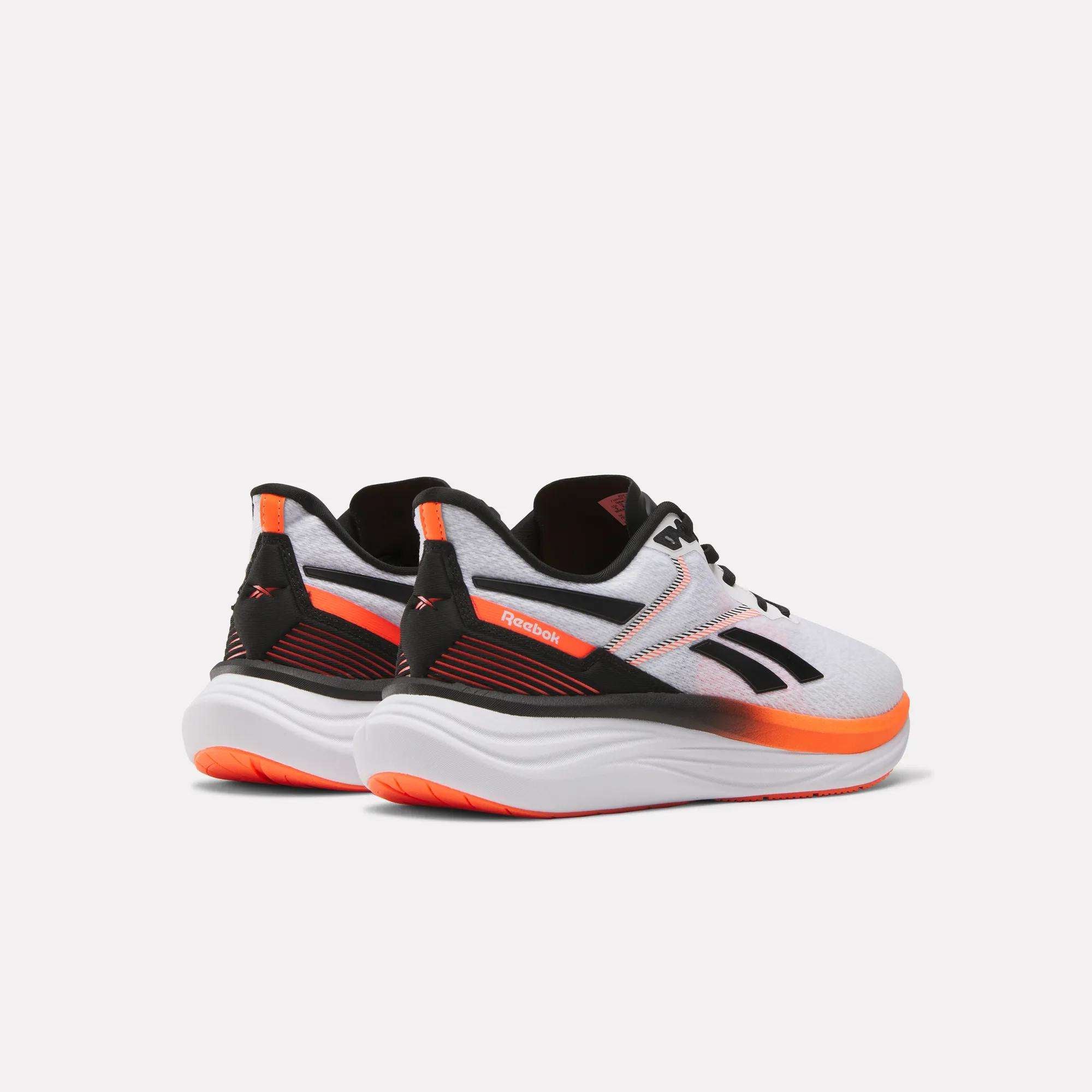 The Reebok Men's Viva Speed Shoes in white with black, orange, and red accents offer extra cushioning and are displayed from the back and side on a plain white background.