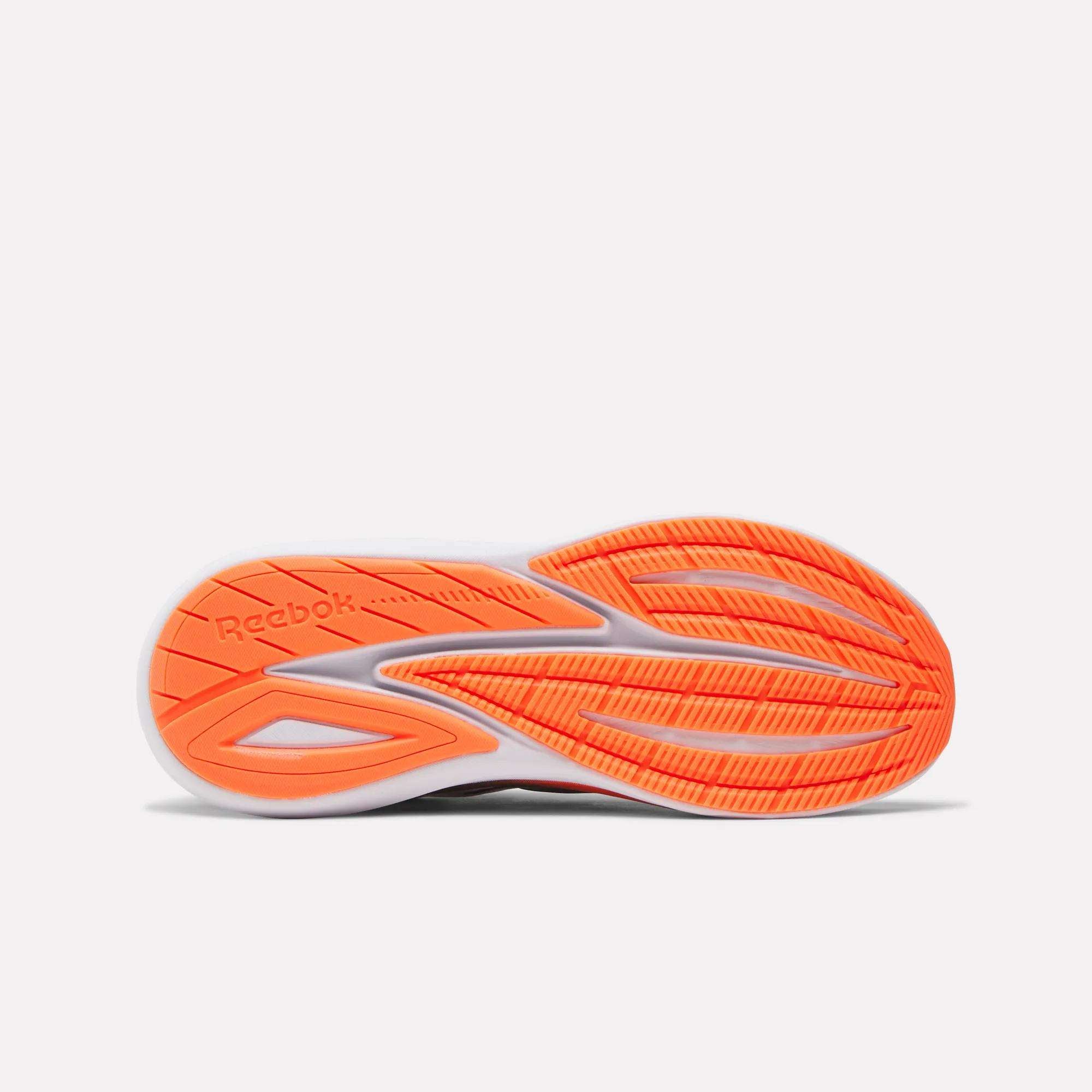 The image displays the sole of the Reebok Men's Viva Speed Shoes, featuring a white base with bold orange tread for traction and extra cushioning, photographed against a plain white background.