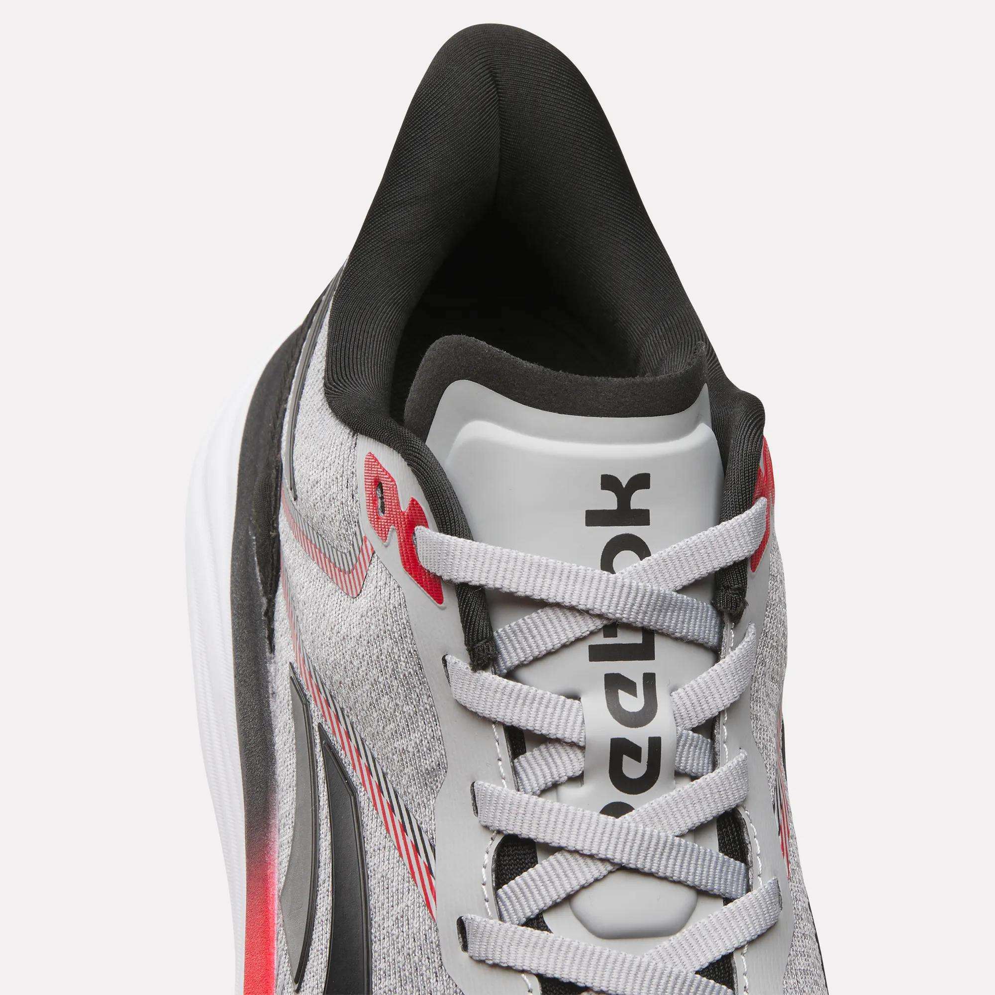 Close-up top view of the Reebok Men's Viva Speed Shoes in gray and white with black and red accents, featuring a breathable mesh upper, visible laces, and a cushioned interior for added comfort.
