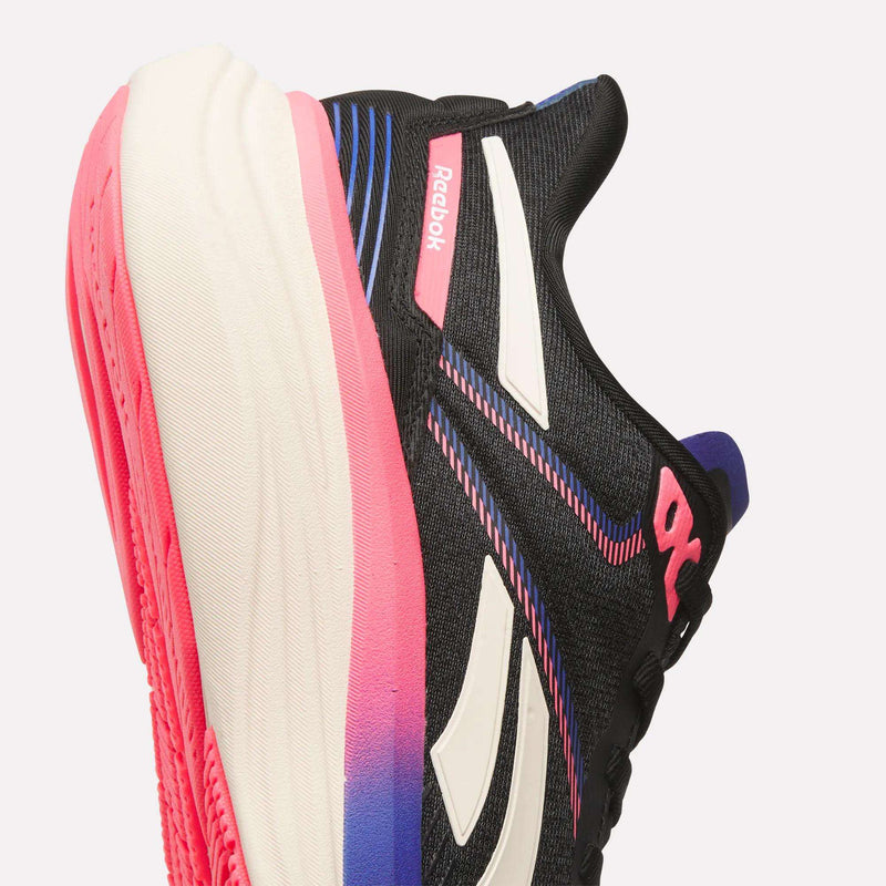 Close-up of the Women's Viva Speed Shoes by Reebok in black with white stripes, pink and blue accents, a thick cushioned white midsole fading to pink and purple, and a bright pink outsole for a breathable athletic look.