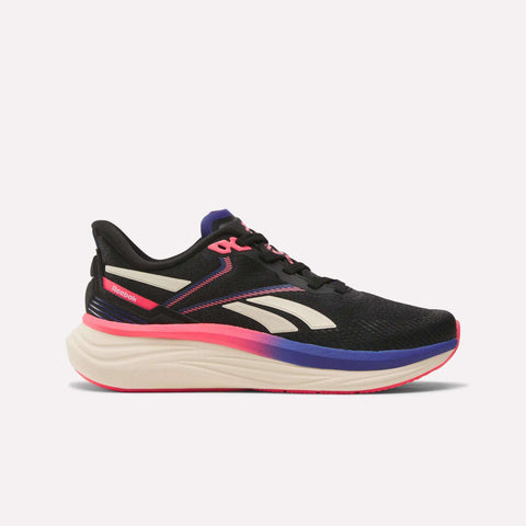 The Reebok Women's Viva Speed Shoes in black feature white and pink details, pink laces, extra cushioning for comfort, and a white sole with blue and pink gradient accents. Shown on a plain white background.
