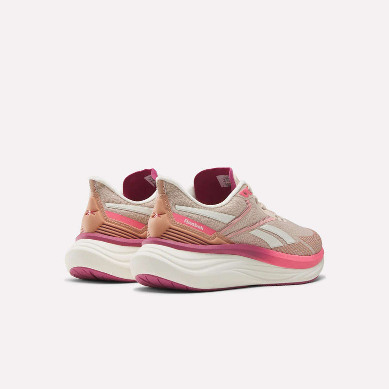A pair of Reebok Women's Viva Speed Shoes in pink and beige, featuring white soles and magenta accents, are shown side by side at an angle on a plain light background.