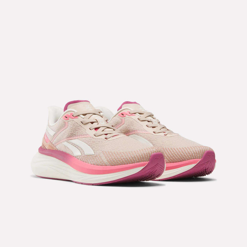The Reebok Women's Viva Speed Shoes, shown side by side on a white background, feature light pink uppers with white and bright pink accents, cushioned soles for comfort, and pink outsoles for breathability.
