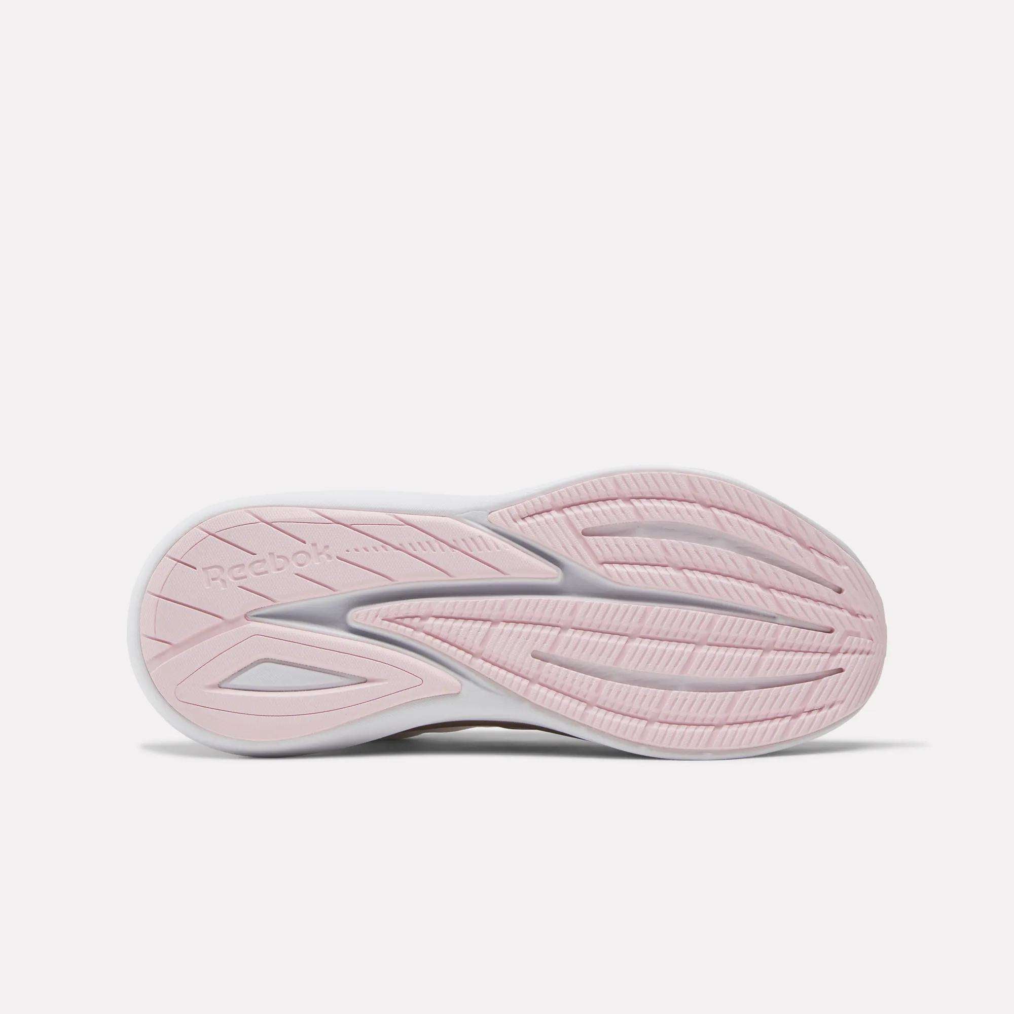 The image displays the sole of Reebok Women's Viva Speed Shoes, viewed from below. The outsole is mainly light pink with white accents, featuring wavy grooves and a textured tread for grip, offering extra cushioning and comfort.