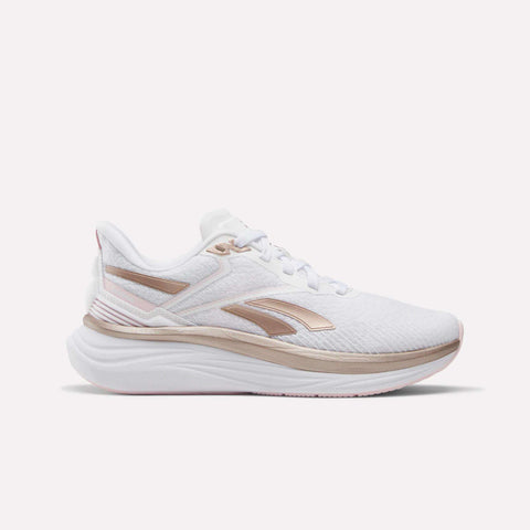 The Reebok Women's Viva Speed Shoes feature a white design with metallic rose gold accents and a thick, cushioned sole, displayed in a side profile against a plain white background.