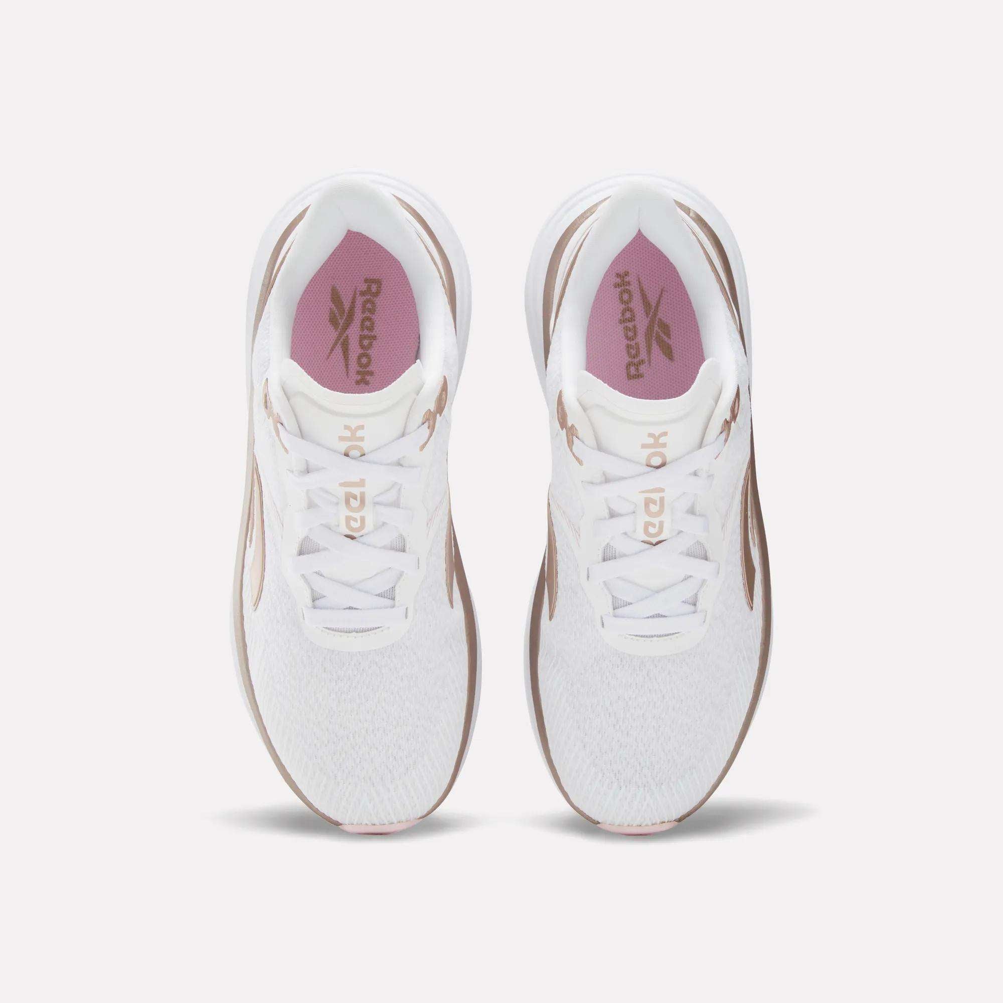 Top view of a pair of Reebok Women's Viva Speed Shoes in white with pink insoles and brown accents, extra cushioning, placed side by side on a light background.