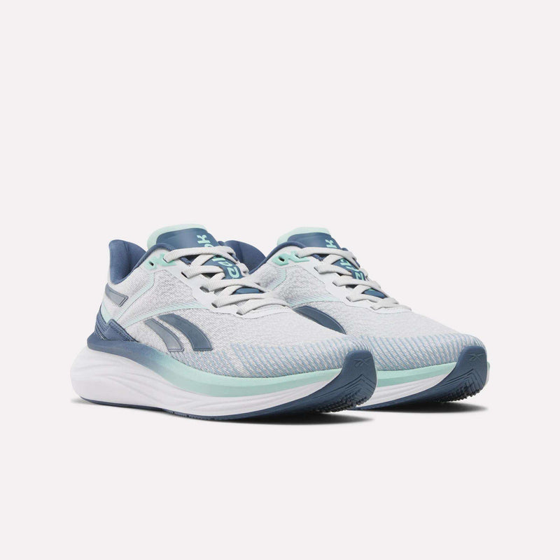 A pair of Reebok Women's Viva Speed Shoes in white and light blue with teal and navy accents, featuring extra cushioning and a breathable mesh upper, shown on a plain white background.
