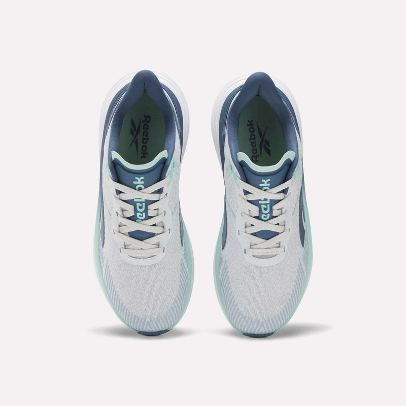 Top view of Women's Viva Speed Shoes by Reebok in white with teal and navy accents, featuring cushioned soles and white laces. The Reebok logo appears on the insoles, all set against a plain white background.