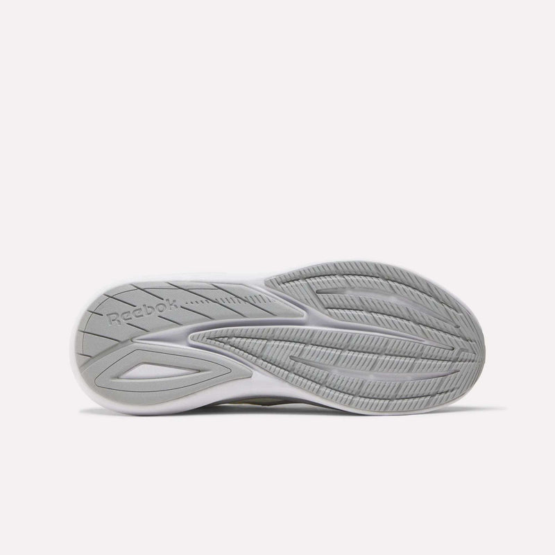 The image displays the sole of Reebok Men's Viva Speed Shoes in white and gray, featuring textured tread patterns, grooves for traction, and the Reebok logo on the left side, emphasizing the shoes’ enhanced cushioning.