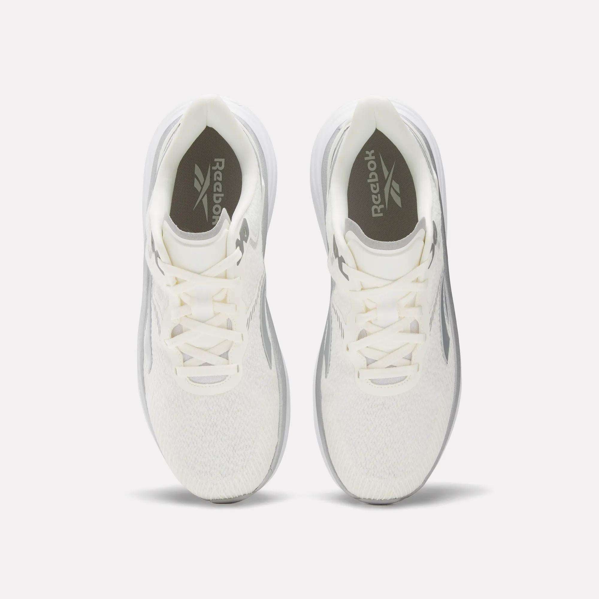 A top view of the Men's Viva Speed Shoes by Reebok, featuring white uppers, light gray side accents, white laces, and gray Reebok logos on the insoles. These breathable shoes are shown on a light background.