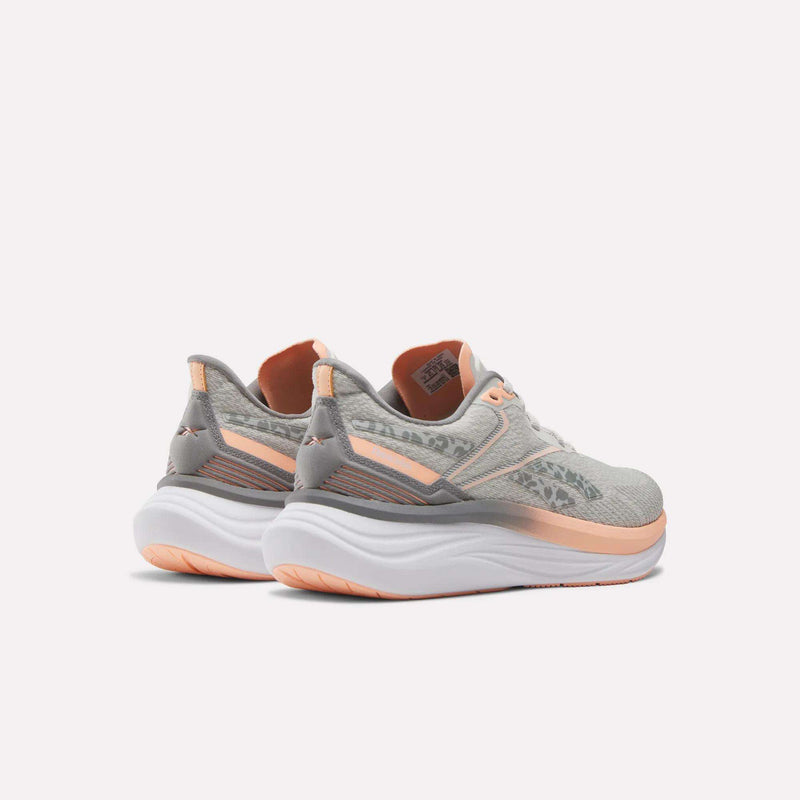 The Reebok Women's Viva Speed Shoes in light gray and peach feature thick white soles for extra cushioning, shown from the back and side against a plain light background.