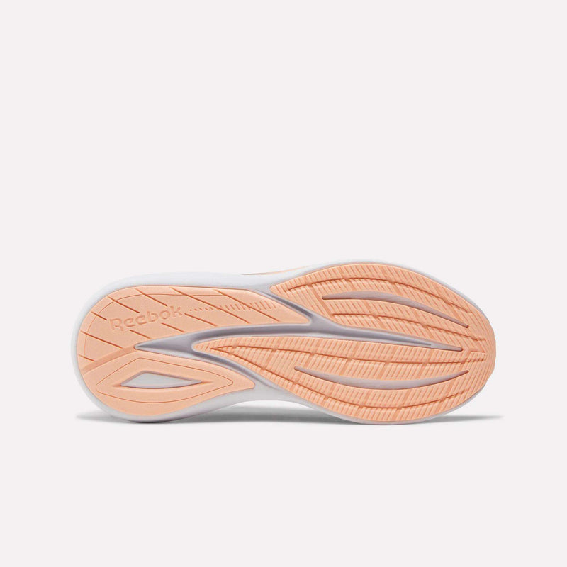 The image shows the sole of the Women's Viva Speed Shoes by Reebok. The peach-colored sole with white accents has extra cushioning, a patterned grip, and features the Reebok logo on the left side.