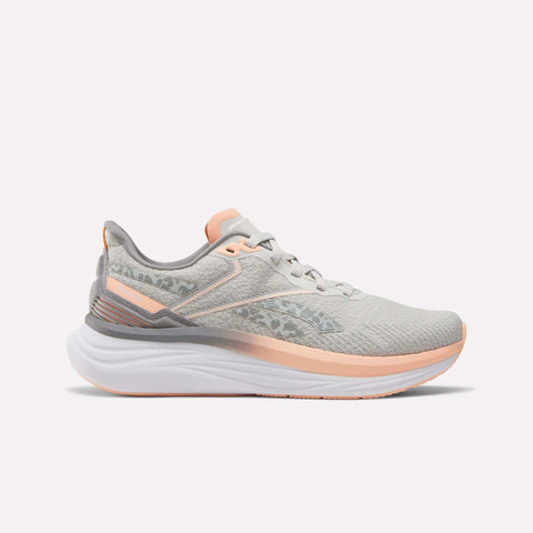The Reebok Women's Viva Speed Shoes feature a light gray design with peach accents, a white cushioned sole for comfort, and a subtle side pattern, shown in profile against a plain white background.