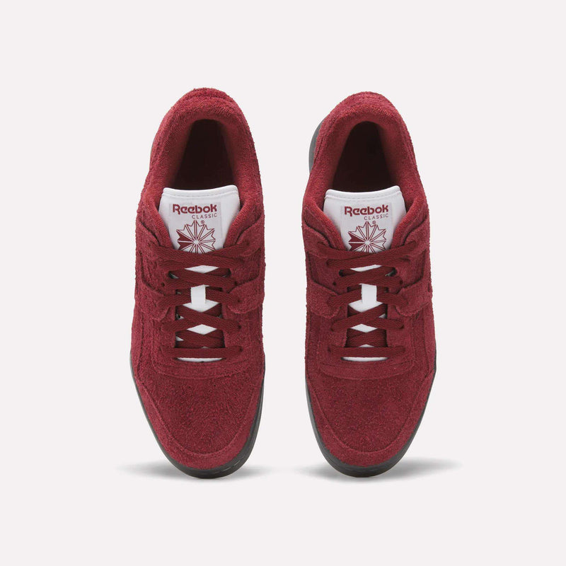 A pair of red Reebok Workout Plus Shoes with white tongues, black soles, and matching red laces and logos is shown from above on a plain white background, highlighting the classic fitness style.