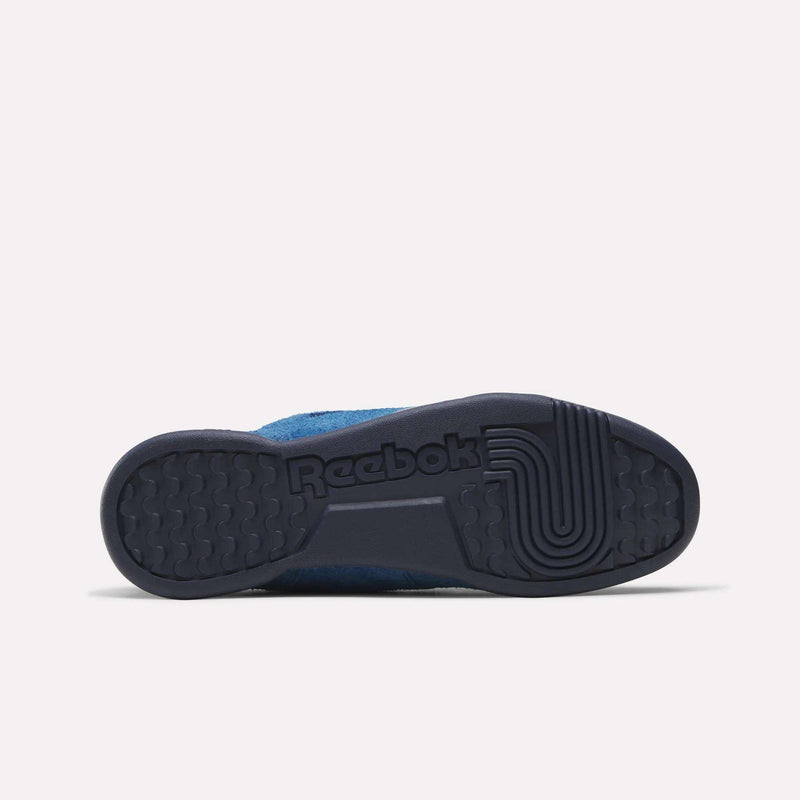 The image displays the sole of the Reebok Workout Plus Shoes in blue, seen from below, highlighting a textured tread pattern and the molded Reebok logo in the rubber.