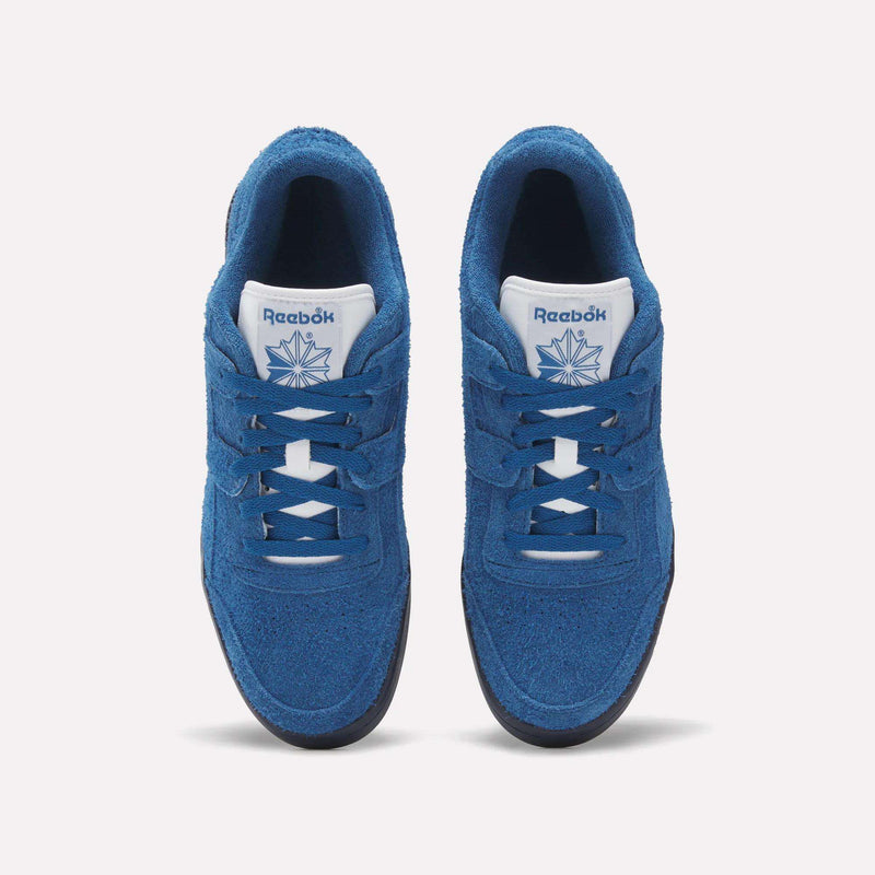 Top view of Reebok Workout Plus Shoes in blue, showing white tongues with the Reebok logo and dark outsoles, placed side by side on a white background—a classic '80s fitness style from Reebok.