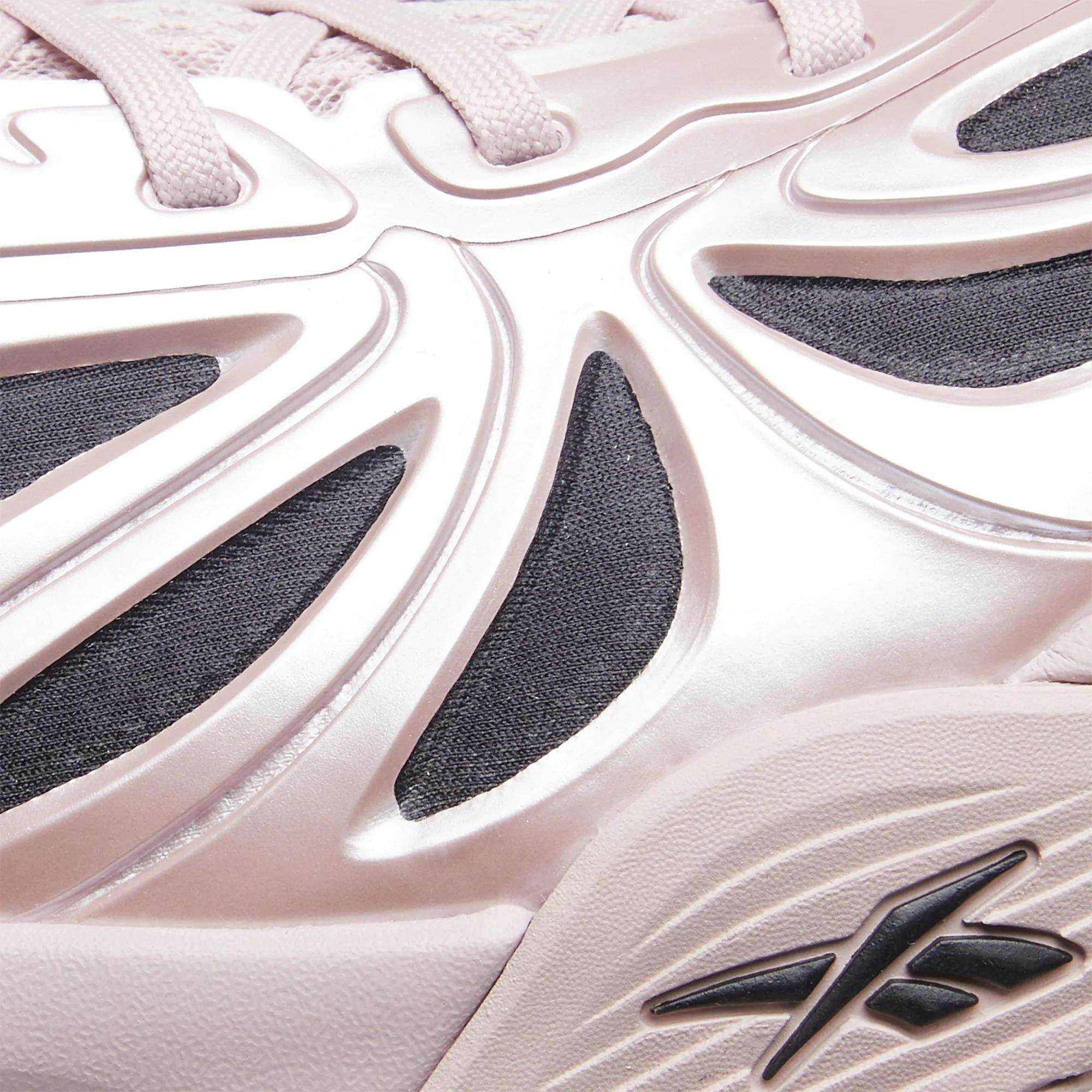 Close-up of a light pink Angel Reese 1 Basketball Shoe by Reebok, featuring textured patterns, black mesh accents, a raised Reebok logo by the sole, and the innovative Energy Return System found in premium performance basketball shoes.