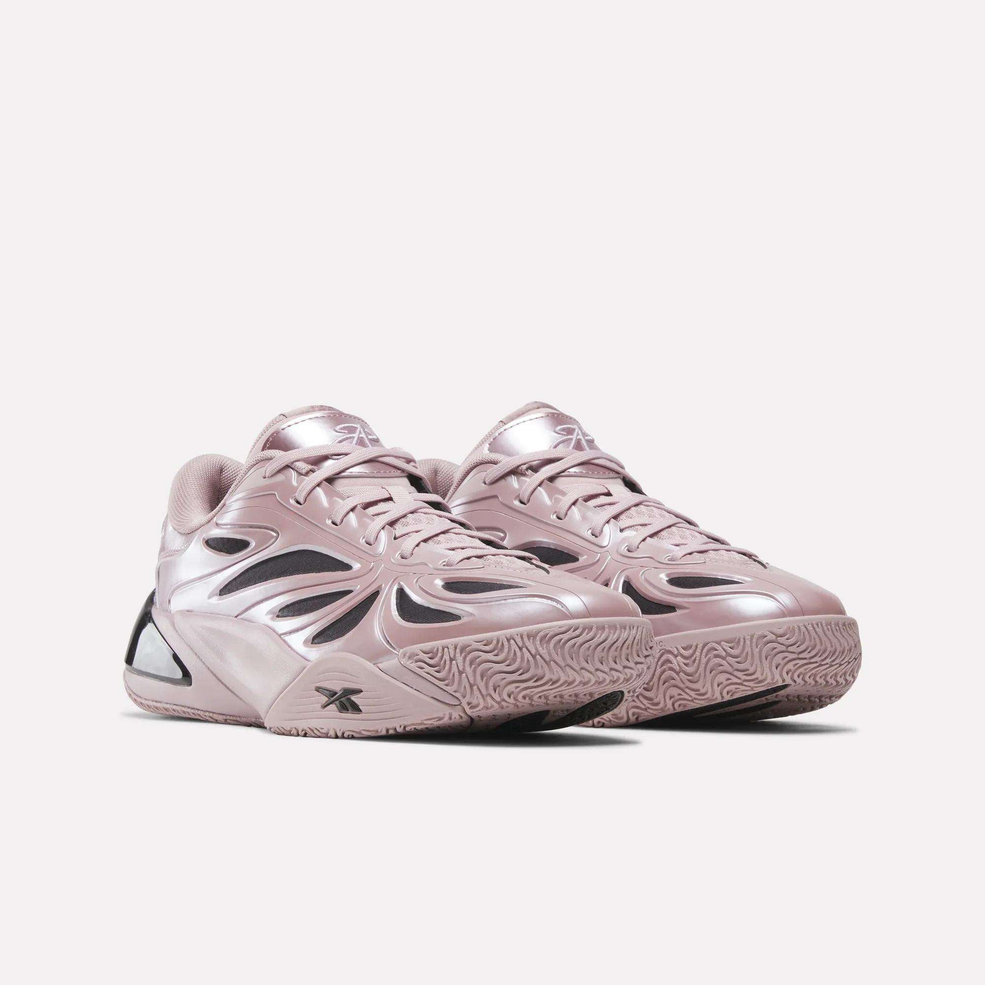 A pair of shiny, light pink Angel Reese 1 Basketball Shoes by Reebok with a futuristic design and textured soles, featuring the Reebok Energy Return System, positioned side by side on a plain light background.