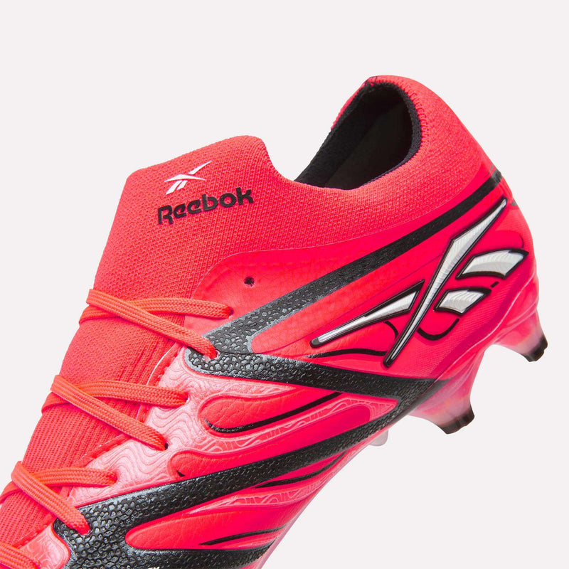 Close-up of a bright red Reebok Sidewinder 26 Elite Firm Ground Cleat, designed for firm grass, featuring black and white accents, detailed stitching, a textured surface for enhanced ball control, and the Reebok logo on the tongue and side.