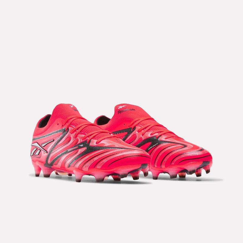 The Reebok Sidewinder 26 Elite Firm Ground Cleats are bright red with black and white accents, showcasing a textured surface for enhanced ball control and molded studs for traction on firm grass, displayed against a white background.