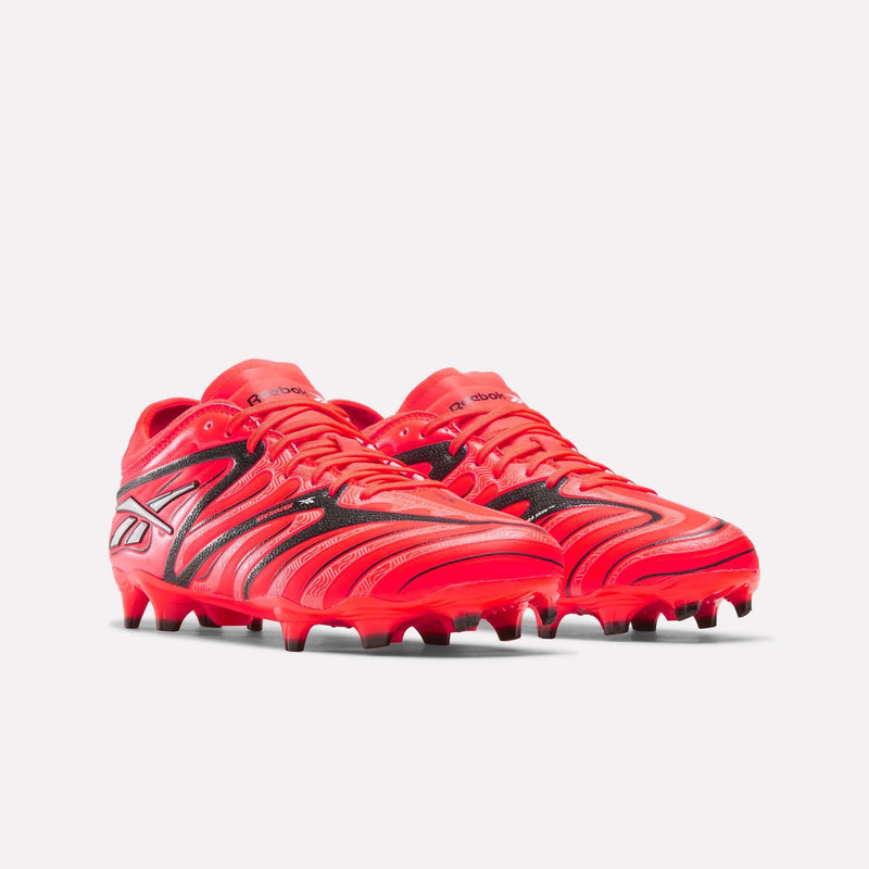 A pair of red Reebok Sidewinder 26 Pro Firm Ground Cleats featuring black wave patterns and branding on the sides, designed for enhanced ball control.