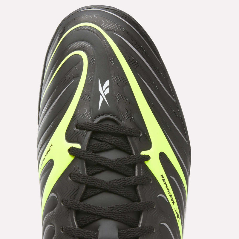 A close-up of the top of the Reebok Sidewinder 26 League Turf Cleats, a black athletic shoe with neon yellow accents and black laces, featuring a white Reebok logo on the tongue—ideal for turf players seeking soccer shoes designed for artificial fields.