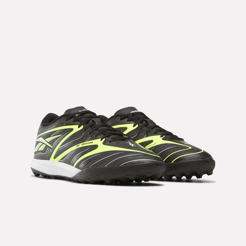 A pair of Reebok Sidewinder 26 League Turf Cleats in black and neon yellow with white soles, designed for turf players on artificial soccer fields.