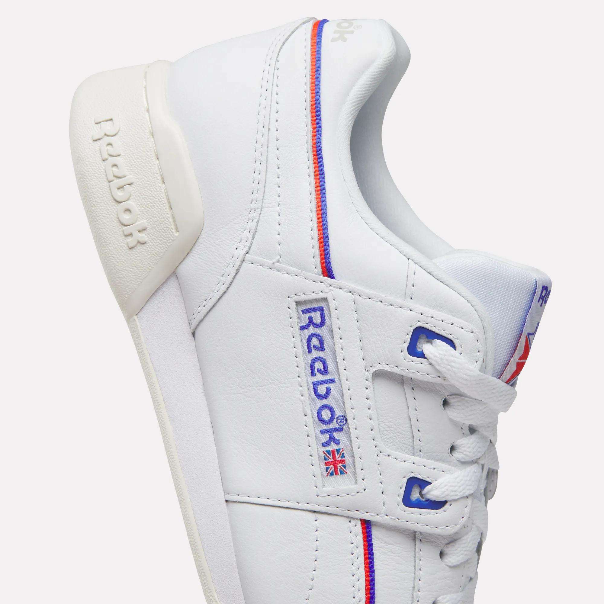The Women's Club C 85 Shoes by Reebok feature white leather, blue and red accents, iconic logos, a small Union Jack flag, white laces, beige heel tab, detailed stitching, and a classic design.