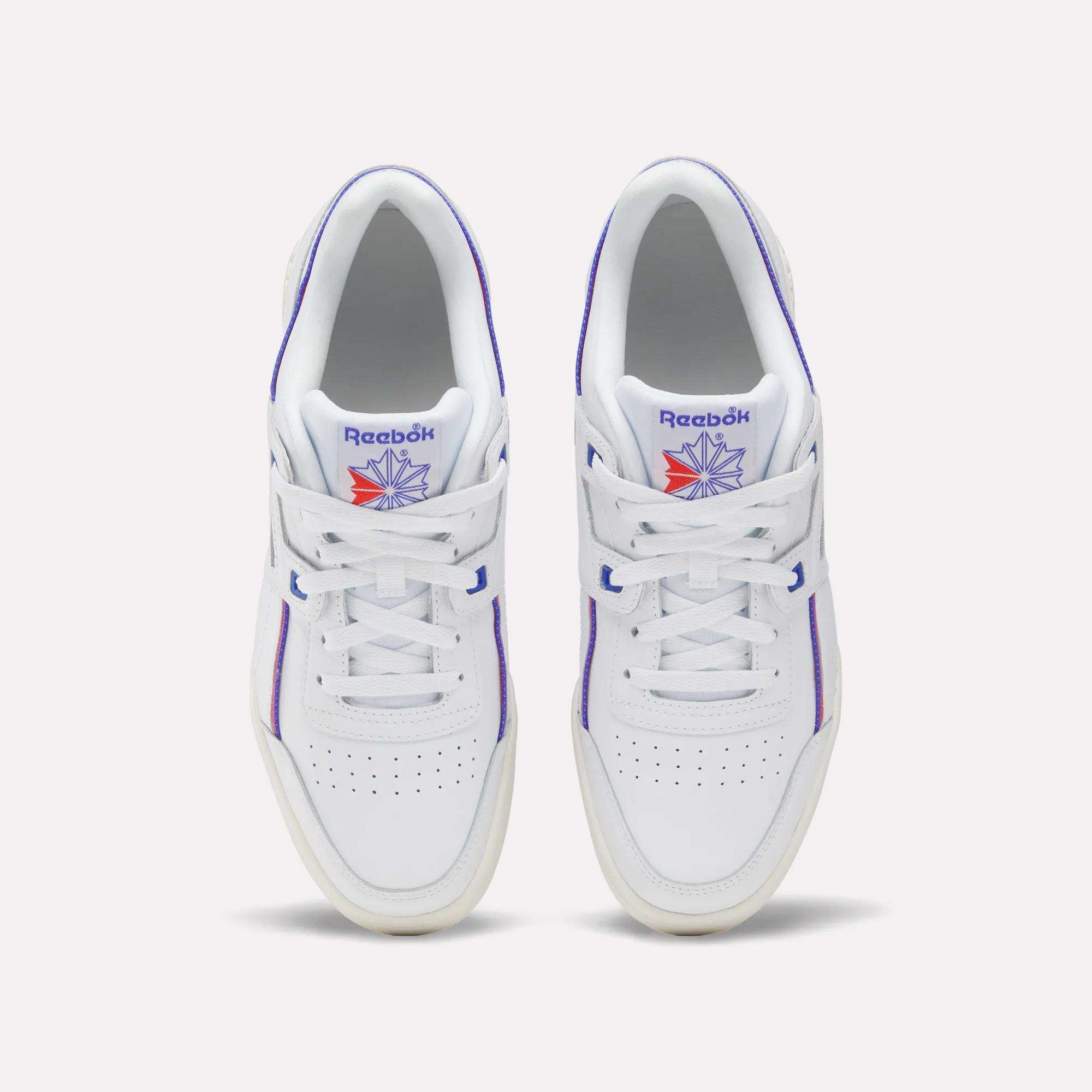 A pair of Women's Club C 85 Shoes by Reebok in white leather with purple accents and a blue and orange Reebok logo on the tongue, shown from above on a light background—classic women's sneakers with timeless style.