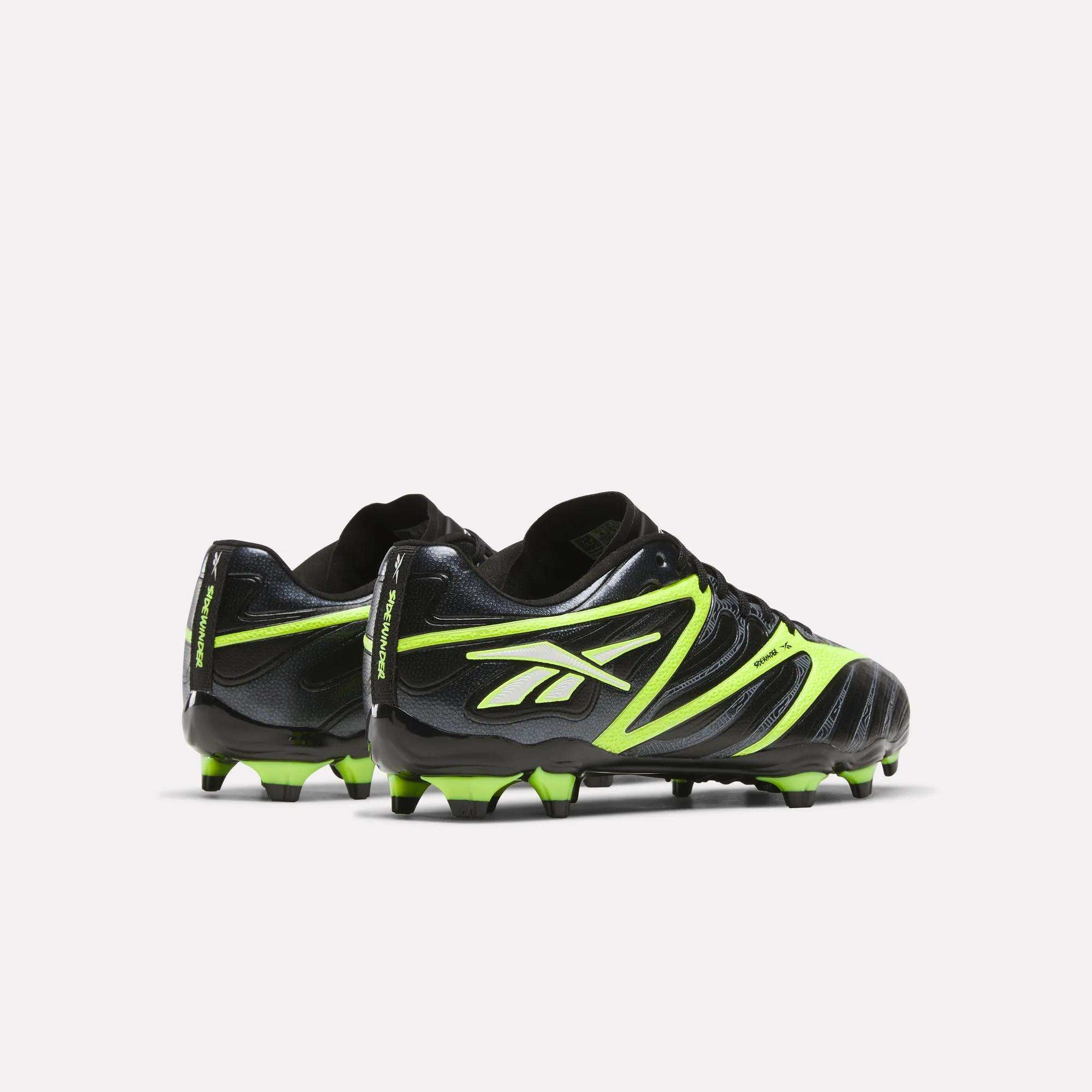 The Reebok Sidewinder 26 League FG Cleats for big kids feature a black design with neon green accents, iconic Reebok logos on the sides, and firm ground studs, shown against a plain white background.