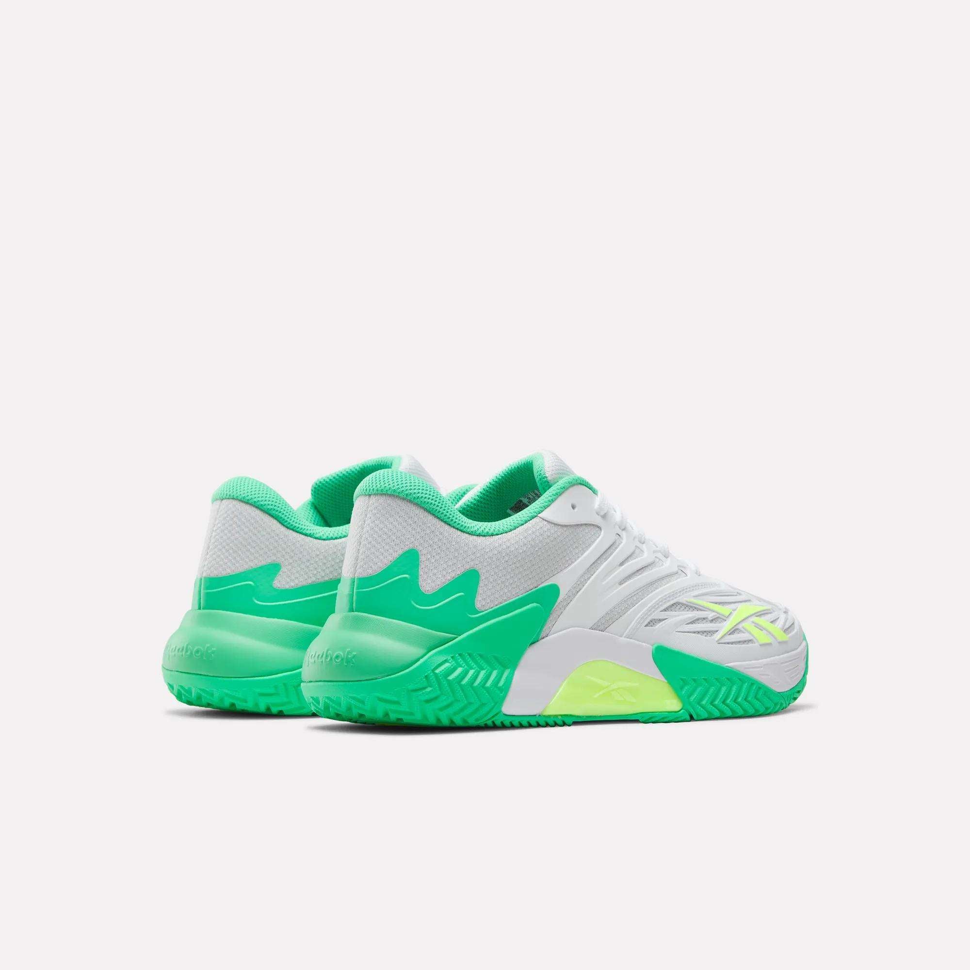 The Reebok Phase EVO Tennis Shoes are shown from a rear-side angle on a white background, featuring white mesh uppers with green and neon yellow accents, plus textured soles for breathability and performance.