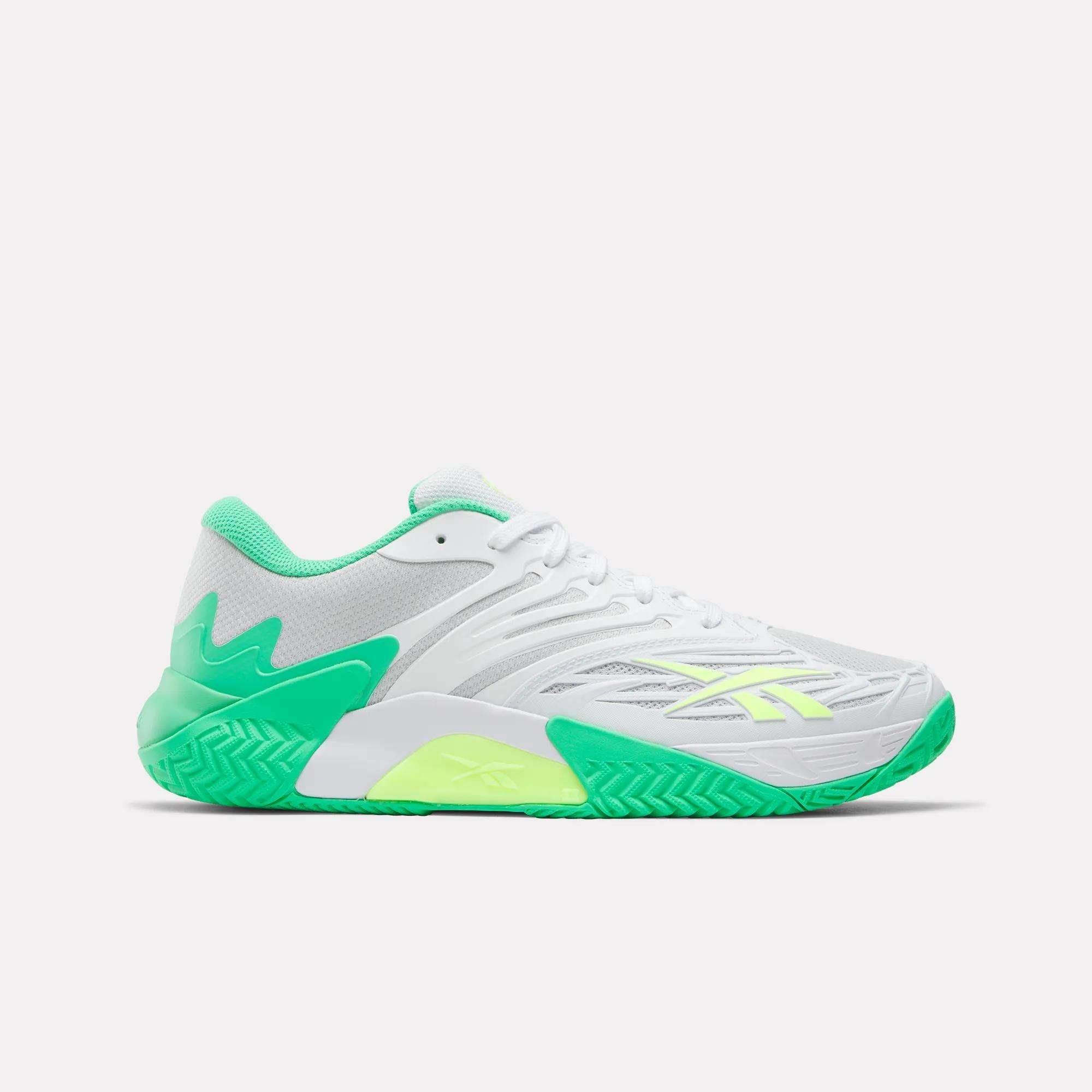 The Reebok Phase EVO Tennis Shoes are white athletic sneakers with green accents, neon yellow details, and a textured green sole, shown in a side profile on a plain white background to highlight their tennis performance style.