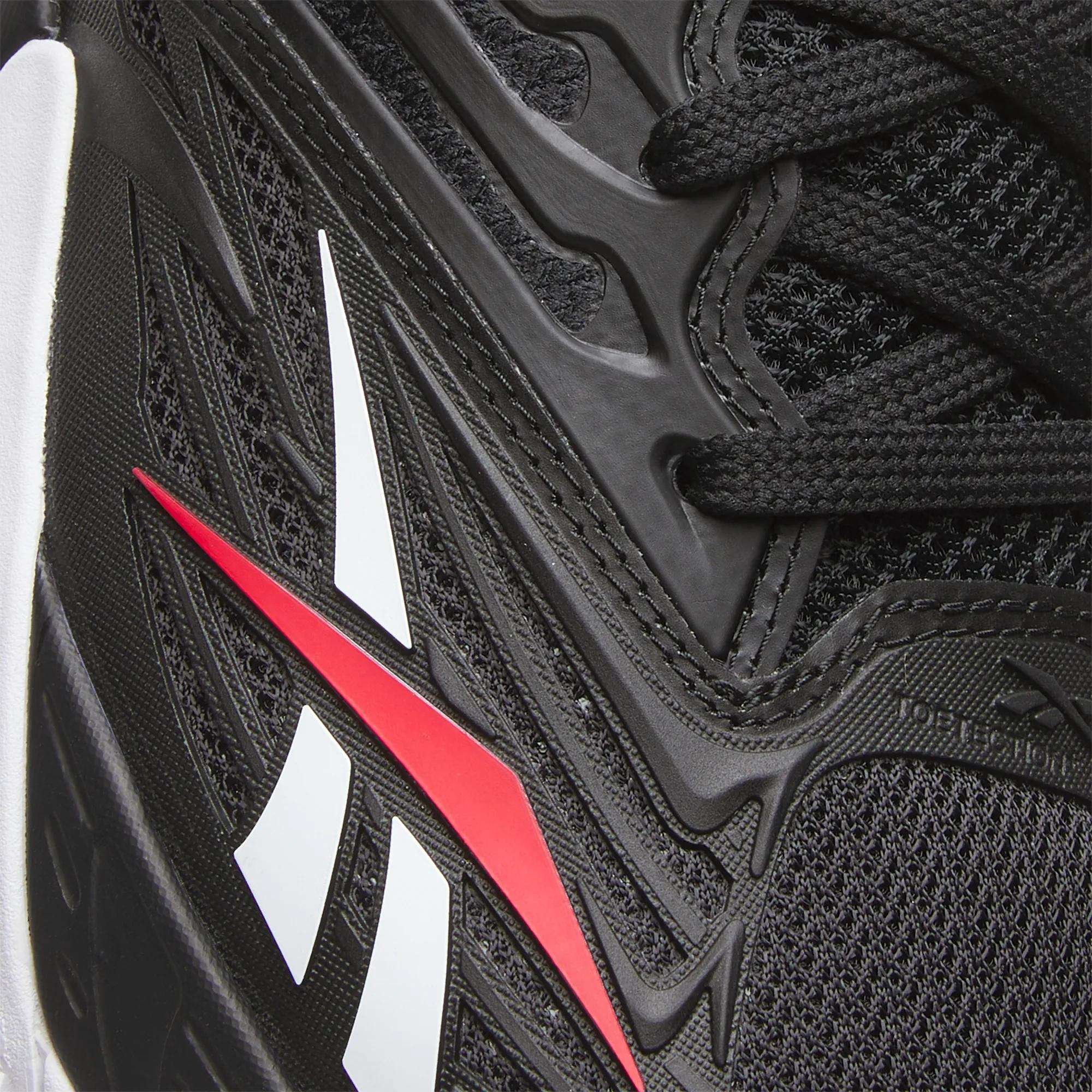Close-up of Reebok Phase EVO Tennis Shoes in black with textured mesh and synthetic overlays, red and white Reebok logo on the side, and black laces—engineered for responsive rebound like top tennis shoes.