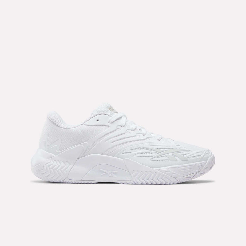The Women's Phase Evo Tennis Shoes by Reebok are white, low-profile athletic sneakers featuring a textured sole and subtle geometric side patterns, showcased against a plain light background.