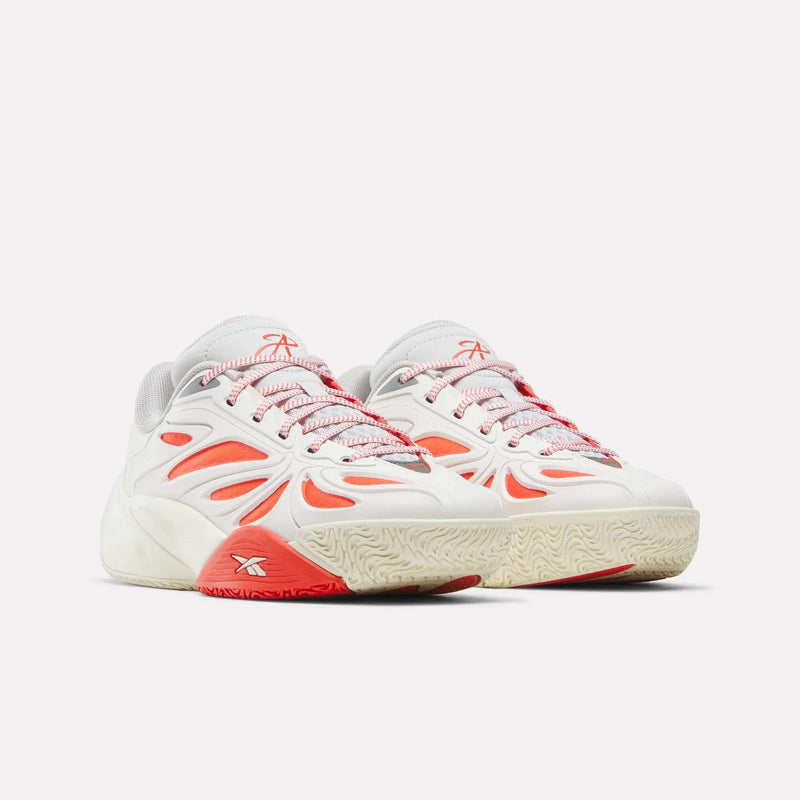 The Reebok Angel Reese 1 Shoes for big kids feature a white base, red and orange accents, mesh details, and textured cream soles, shown side by side against a plain light background.