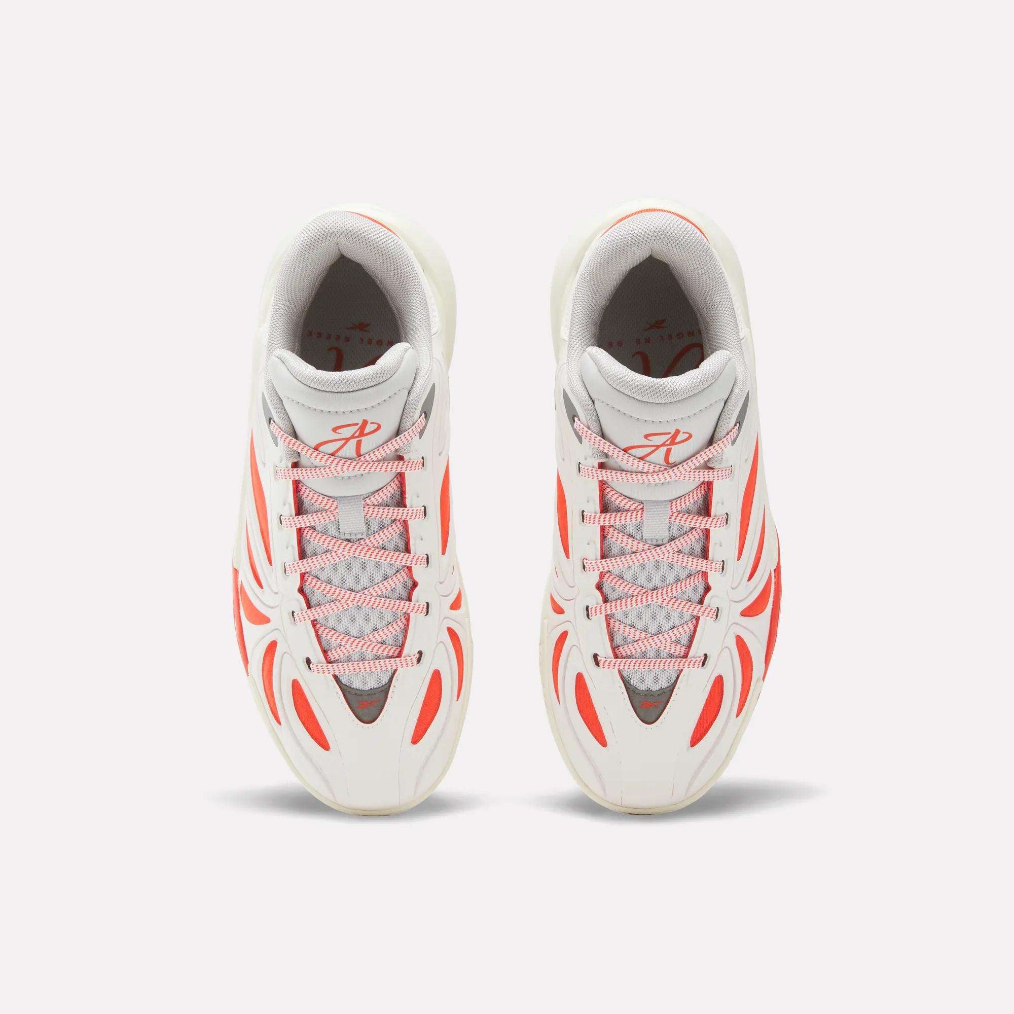 Top view of Reebok Angel Reese 1 Shoes for big kids in white with gray accents and bold orange lines and lace loops, placed side by side on a light background.