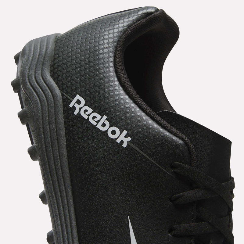 Close-up of a black Reebok Strike Turf Soccer Shoe featuring textured dots, a silver Reebok logo, and a gray cleated sole—ideal for soccer practice. Only part of the shoe and its laces are shown.