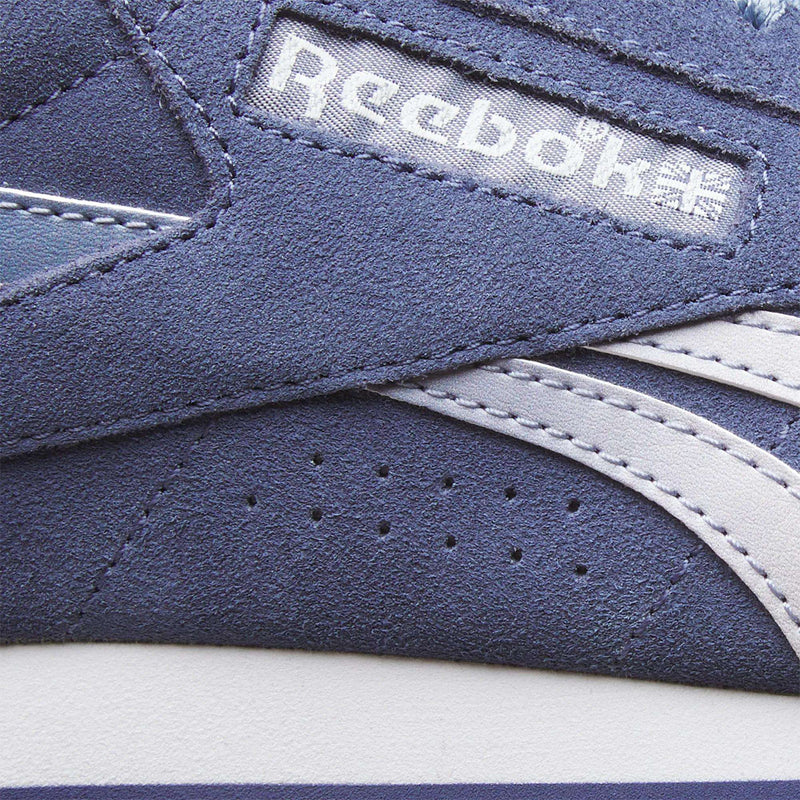 Close-up of a blue Women’s Freestyle Lo shoe side panel featuring the Reebok logo and name on a heritage-inspired woven patch.