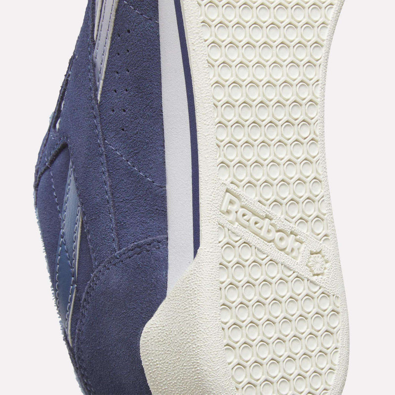 Close-up view of the underside of a blue Women’s Freestyle Lo shoe showing the circular tread pattern and Reebok brand name embossed on the sole.
