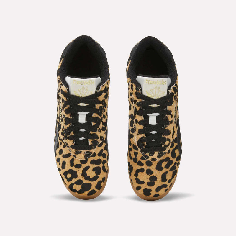 A pair of Reebok Women's Freestyle Lo Shoes with a bold leopard print pony hair upper, black laces and accents, and white tongues featuring the gold Reebok logo, inspired by classic '80s fitness trainers, viewed from above on a white background.