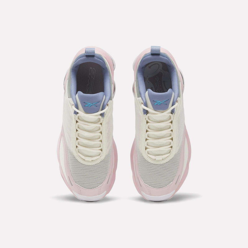 Top view of a pair of Reebok Women's DMX Series 3000 Training Shoes in white, cream, and light pink with mesh toes, lavender tongues, blue pull tabs, and white laces on a plain light background. These cushioned shoes are designed with DMX 3 Technology for superior comfort with every step.