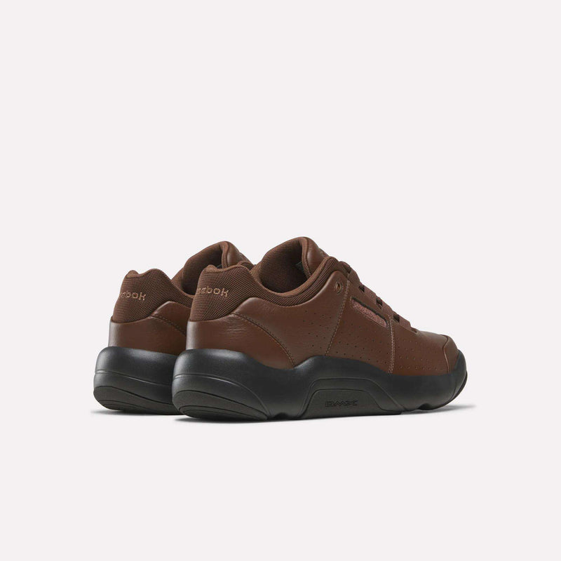 A pair of Reebok DMX Comfort+ Classic sneakers in brown premium leather with black soles, shown from the back left side against a plain white background.