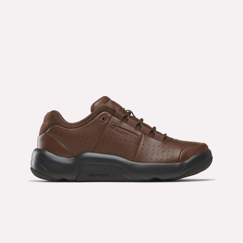 The Reebok DMX Comfort+ Classic in Formal Brown/Formal Brown/Black features premium leather construction, perforated detailing, a black sole, and a lace-up closure. The athletic walking shoe is displayed in side profile against a plain white background.