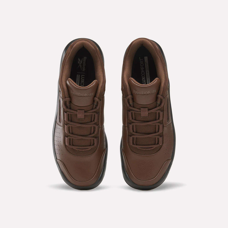 A pair of Reebok DMX Comfort+ Classic sneakers in brown premium leather are displayed from an overhead perspective, highlighting their lace-up fronts, perforated toe boxes, and Reebok branding on the tongues. The shoes feature black outsoles and are positioned side by side against a white background.