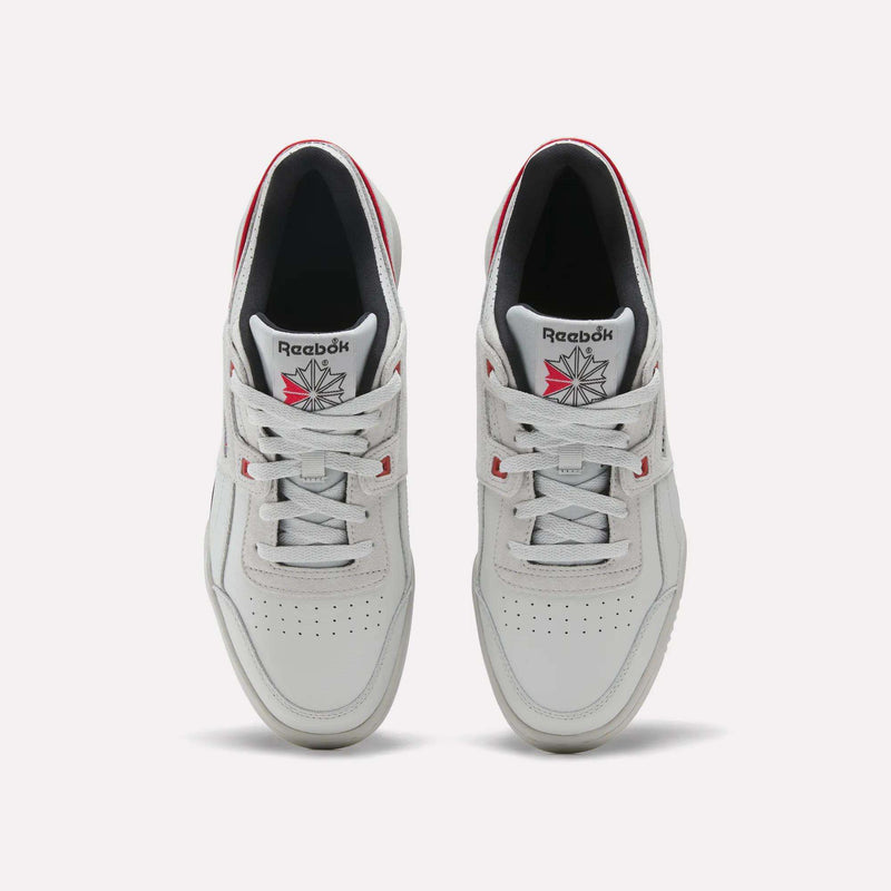 A top-down view of a pair of Reebok Workout Plus shoes in white with red accents and the Reebok logo on the tongue, featuring subtle vintage details against a plain light gray background.