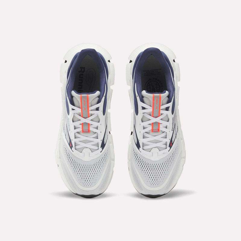 Top view of a pair of Reebok Men's FloatZig 2 Running Shoes with white mesh toes, navy interiors, Superfloat+ cushioning, and orange tongue branding, displayed side by side on a plain white background.